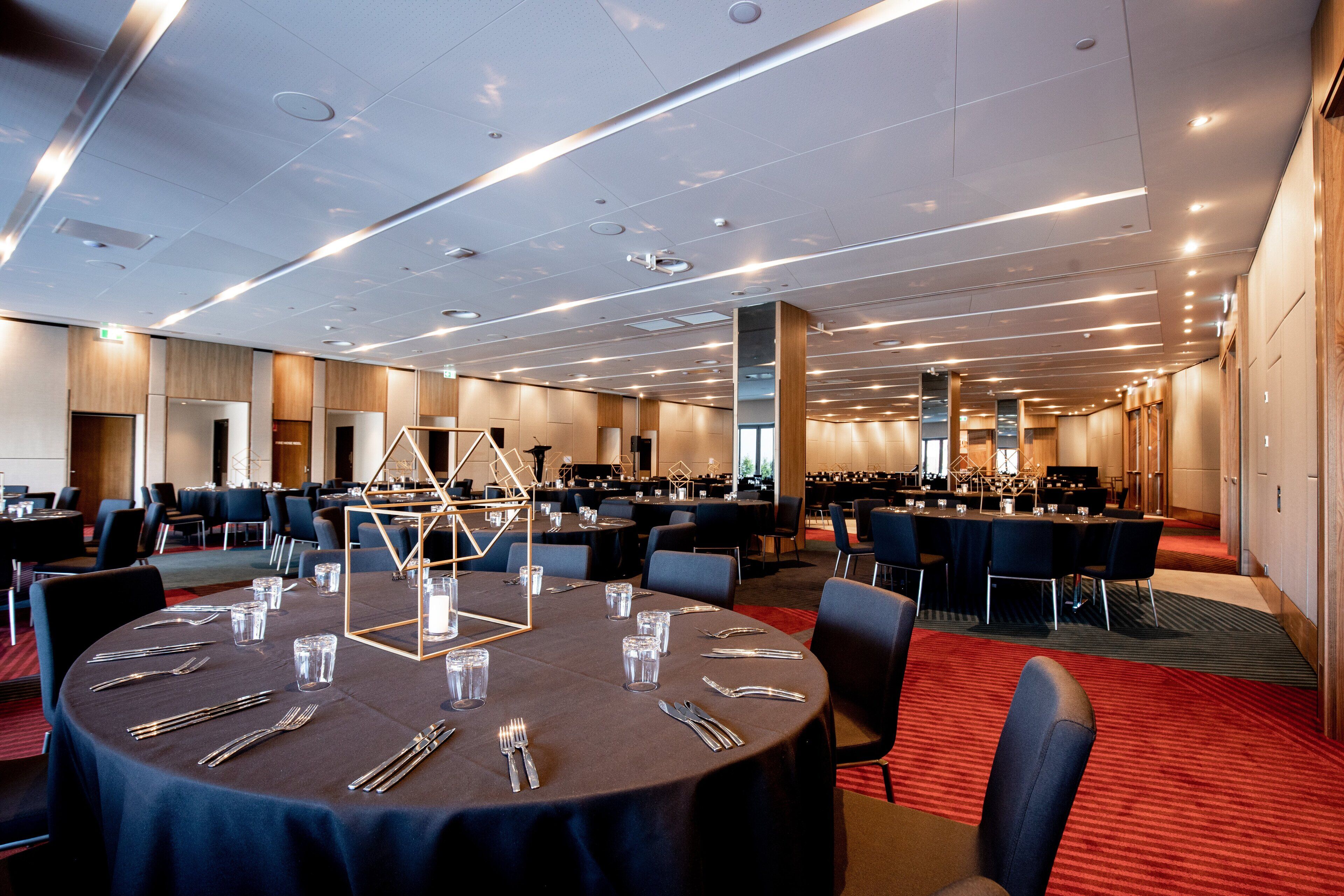 A conference room with round tables, chairs, and a stage area.