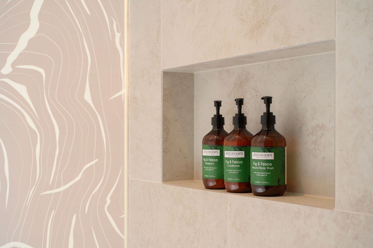 Tres botellas de jabón de Antipodes para manos y cuerpo sobre una estantería.