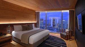 Een moderne hotelkamer met een groot bed, een zithoek en uitzicht op de stad.