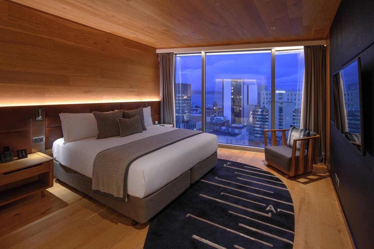 Een moderne hotelkamer met een groot bed, een zithoek en uitzicht op de stad.