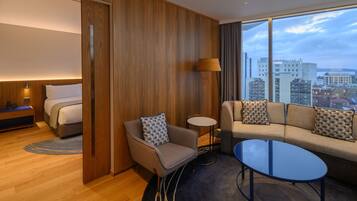 A modern hotel room with a bed, a sofa, a small table, and a chair.