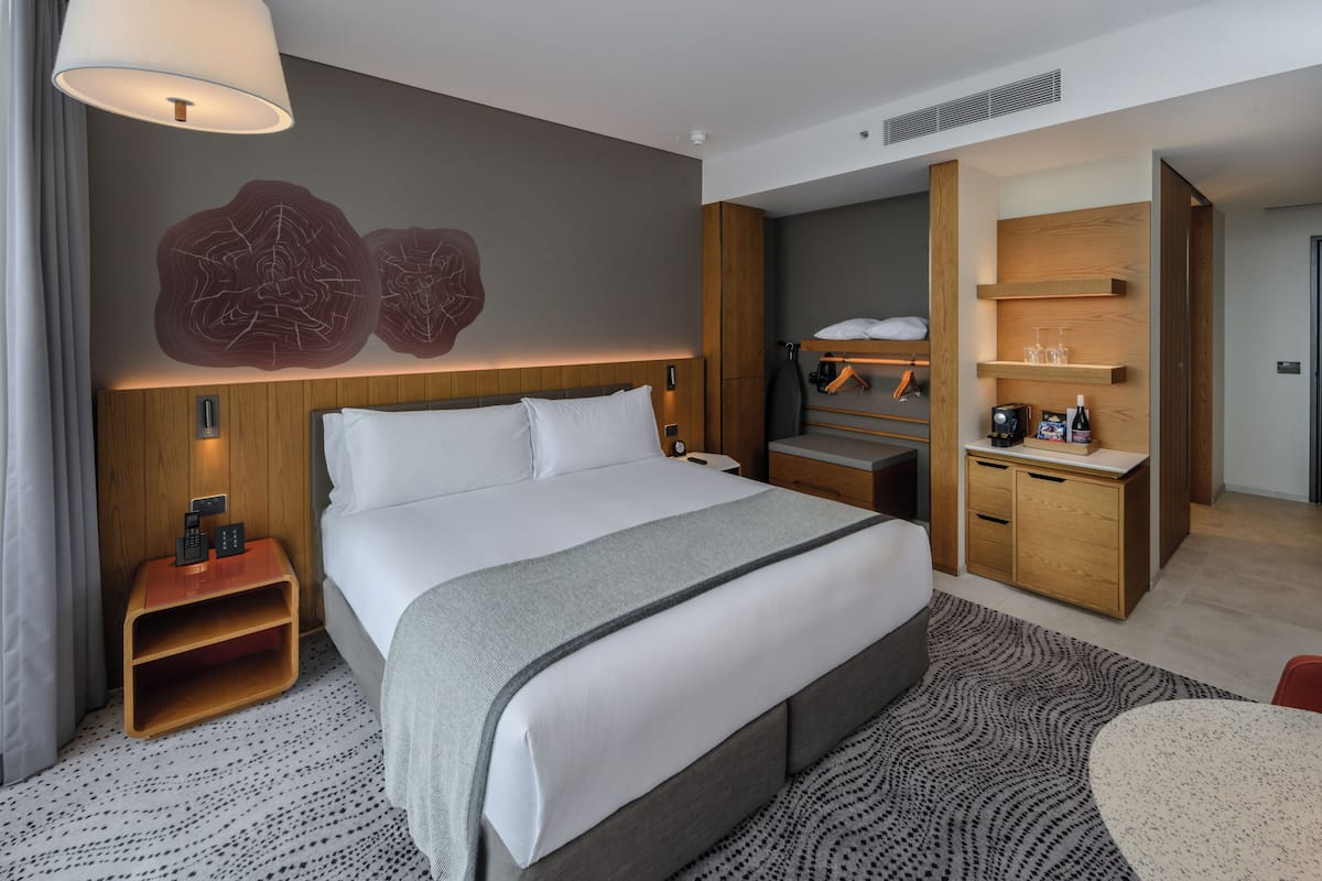 Een moderne hotelkamer met een groot bed, nachtkastjes, een bureau en een kledingkast.