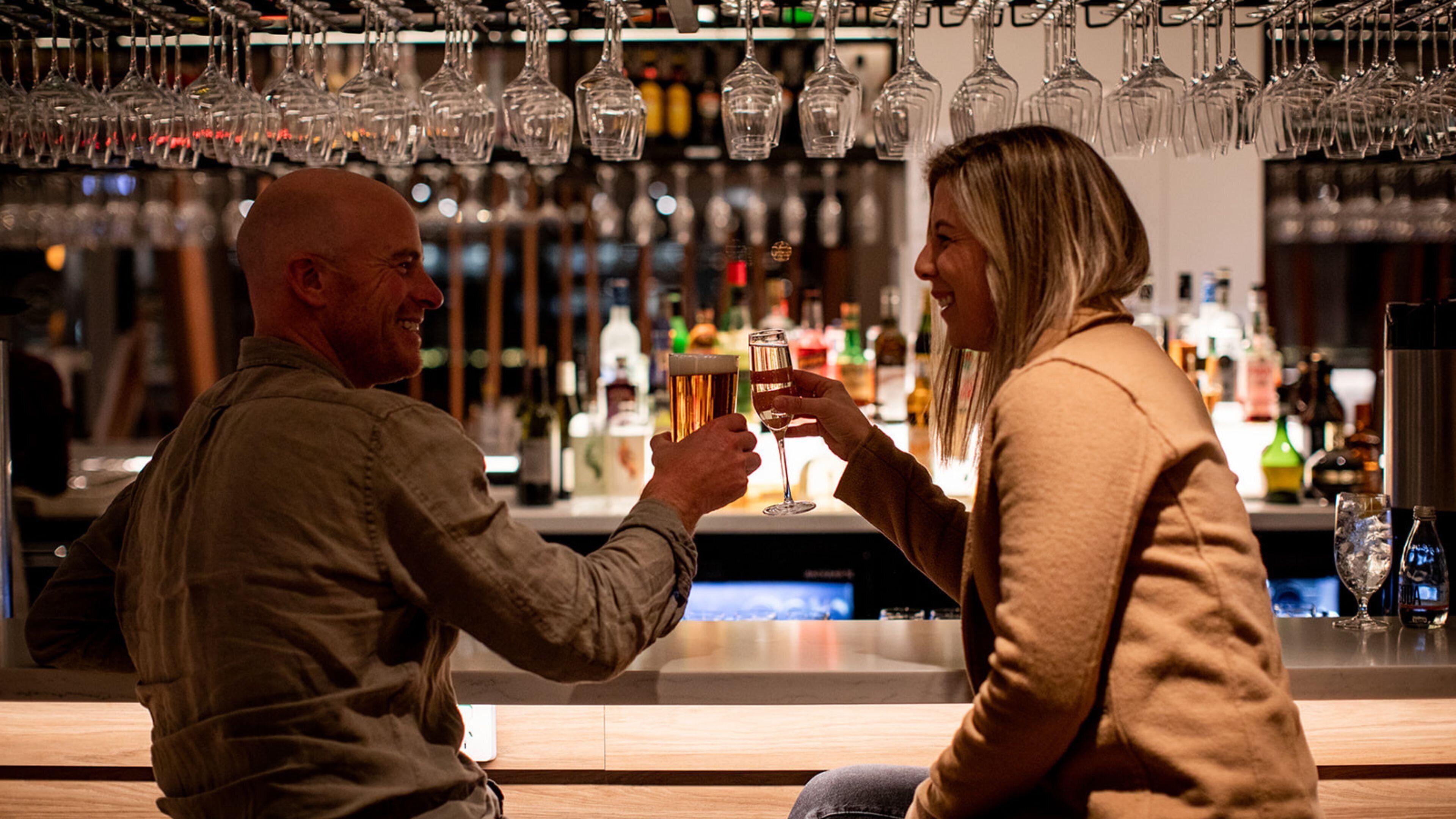 A bar setting with multiple glasses hanging above the bar counter.