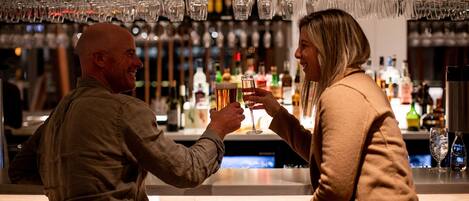 A bar setting with multiple glasses hanging above the bar counter.