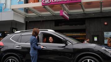Un SUV negro estacionado frente a un edificio con un letrero que dice "CROWNE PLAZA".