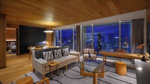 A modern living room with a sofa, armchair, coffee table, and city view.