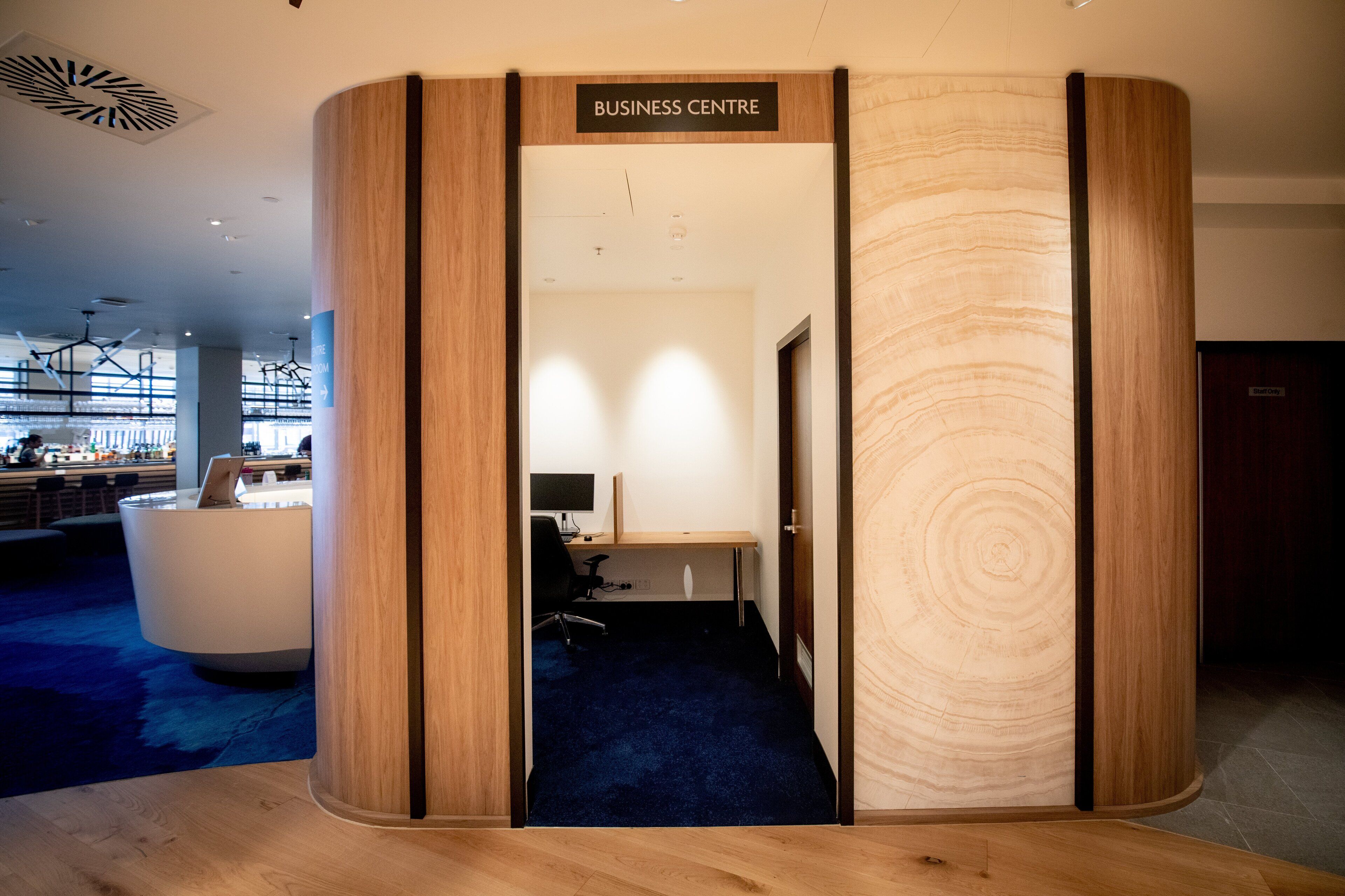 A business center with a wooden reception desk, a computer, and a blue carpeted floor.