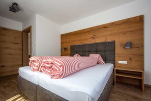 A bedroom with a bed, wooden headboard, bedside tables, and a wooden wardrobe.