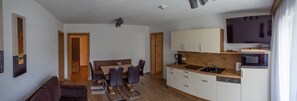 A compact kitchen with a dining area, a flat-screen TV, and a built-in oven.