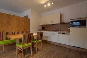 A modern kitchen with wooden cabinets, a microwave, and a dining area with a bench and chairs.
