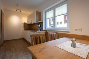 A small kitchen with wooden cabinets, a coffee machine, and a window with blinds.