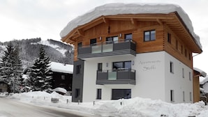 A multi-story building with balconies, labeled 'Appartments Steffi,' surrounded by snow-covered trees and a mountainous backdrop. - Rotflüh - Apartments Steffi (Tannheim)