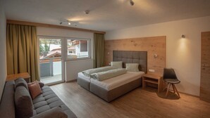 A bedroom with a bed, a sofa, a chair, and a wooden headboard. - Rotflüh - Apartments Steffi (Tannheim)