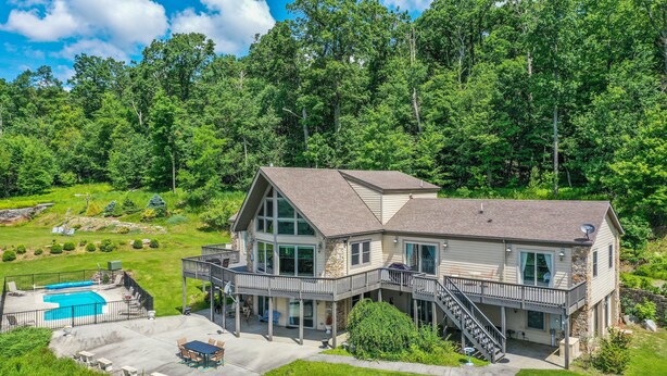 A two-story house with a large deck, a swimming pool, and a stone facade. - Dream Big (Swanton)