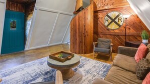 A cozy loft-style room with a wooden accent wall, a teal door, and a round table with a tray.