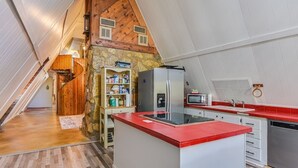 A kitchen with a central island, a stone wall, and a wooden ceiling.