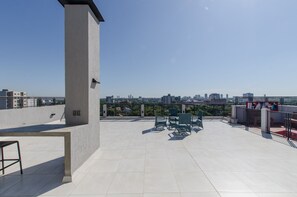 Terraza en la azotea con vistas a la ciudad, que incluye un espacio de estar con sillas y una mesa.