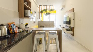 Uma cozinha moderna com ilha central, micro-ondas embutido e televisão na parede.