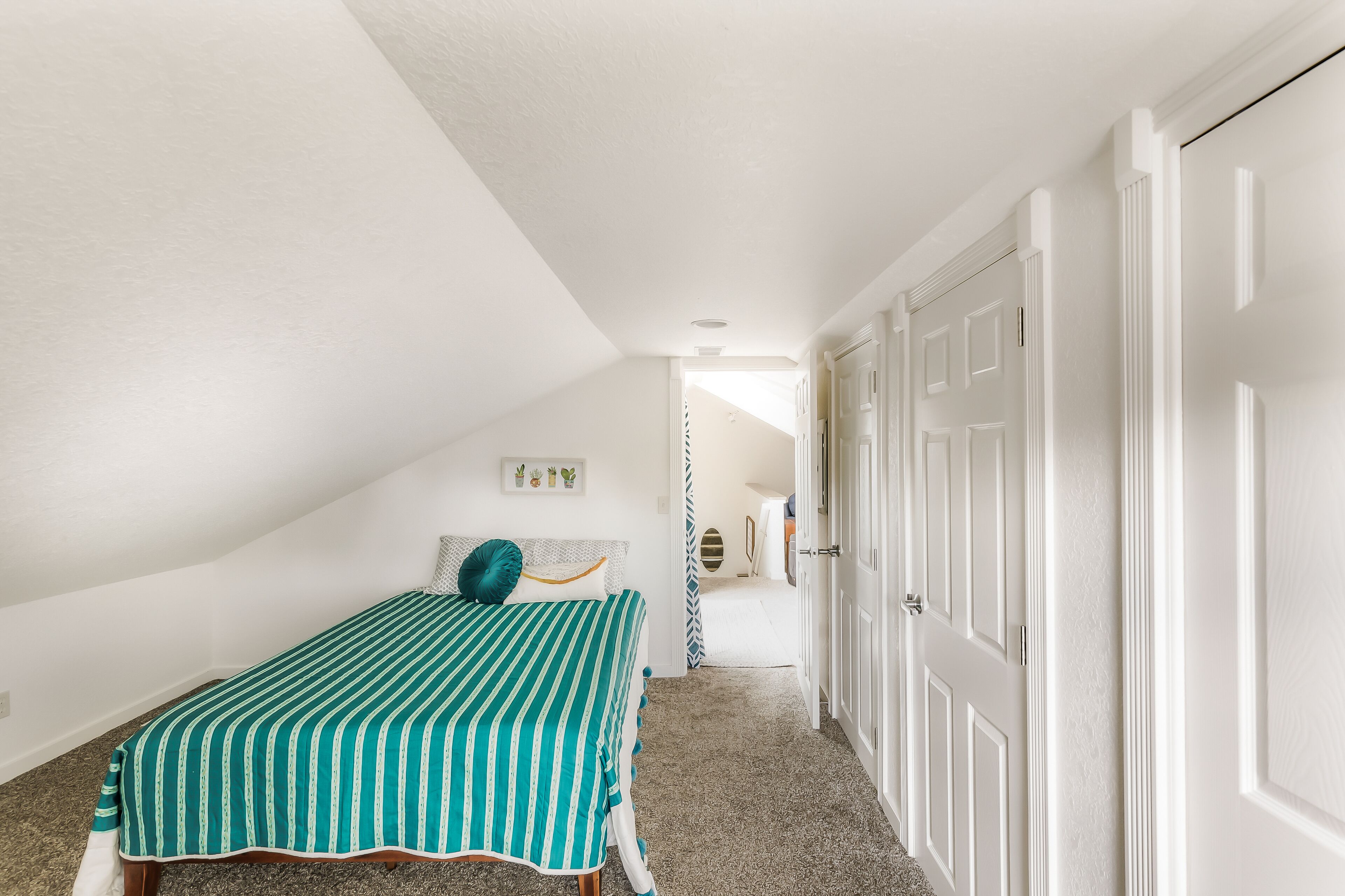 Un dormitorio con una cama, una puerta y un pasillo que conduce a otra habitación.