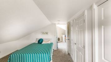 Un dormitorio con una cama, una puerta y un pasillo que conduce a otra habitación.