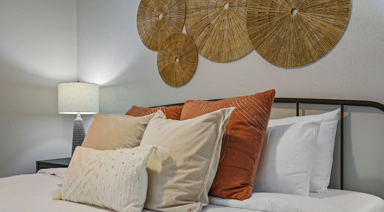 A neatly made bed with multiple pillows, a bedside lamp, and decorative wall art.