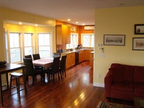 Una sala de estar amplia con un sofá rojo, un comedor con mesa y sillas, y una cocina con armarios de madera y una ventana.