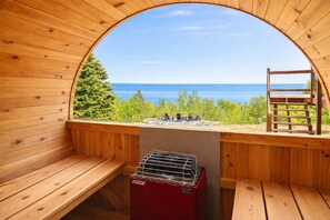 Una sauna de madera con vistas al mar y al follaje.