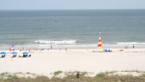 Een strand met mensen, parasols en een kegelvormige vlag.