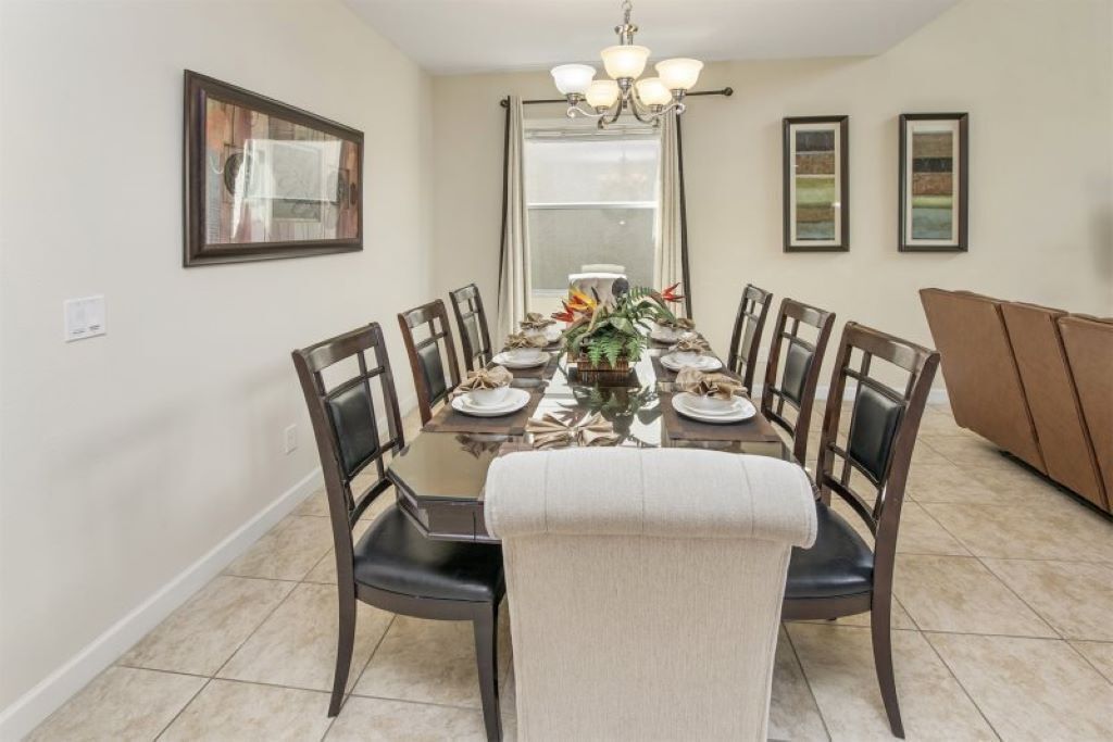 A dining room with a rectangular table, six chairs, and a chandelier.