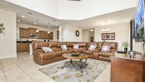A spacious living room with a sectional sofa, a coffee table, and a kitchen in the background. - Only Minutes to Disney (Kissimmee)