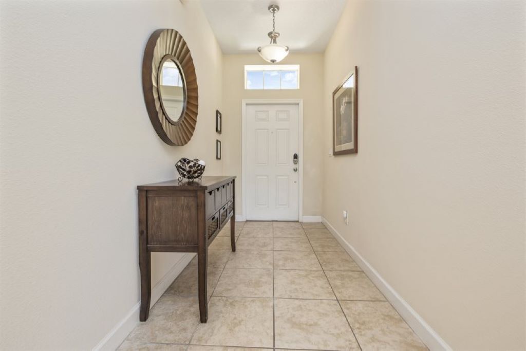 A hallway with a wooden console table, a large mirror, and a white door.