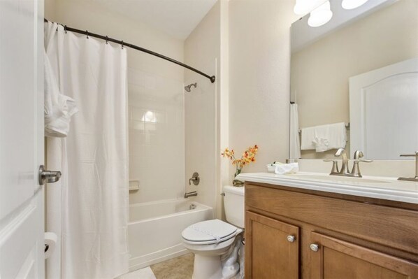 A bathroom with a bathtub, toilet, and vanity.