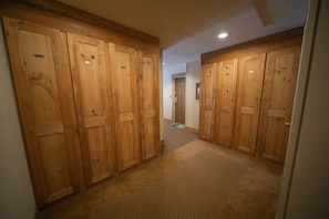 A hallway with wooden double doors, carpeted floor, and a small door in the background.