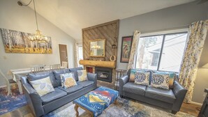 A living room with a fireplace, two sofas, a coffee table, and a chandelier. - Family-Friendly, Updated Condo w/Outdoor Pool (Keystone)