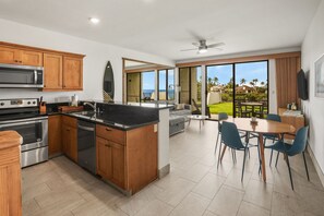 A modern kitchen with a central island, built-in appliances, and a dining area with a view. - Modern + Serene Oceanfront Napili Getaway W/AC - No parking or resort fees (Lahaina)