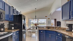 Une cuisine moderne avec des armoires bleues, des comptoirs en granit et un réfrigérateur noir.
