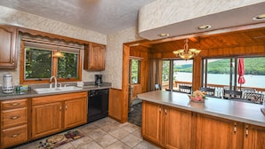 A kitchen with wooden cabinets, a dishwasher, and a large window overlooking a lake.