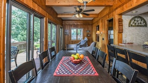 A wooden interior with a dining table, chairs, and a fruit bowl.