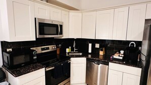 A modern kitchen with white cabinets, a stainless steel microwave, oven, and dishwasher. - Sosuite | Arcade 2BR Apt w/ W/D (Philadelphia)