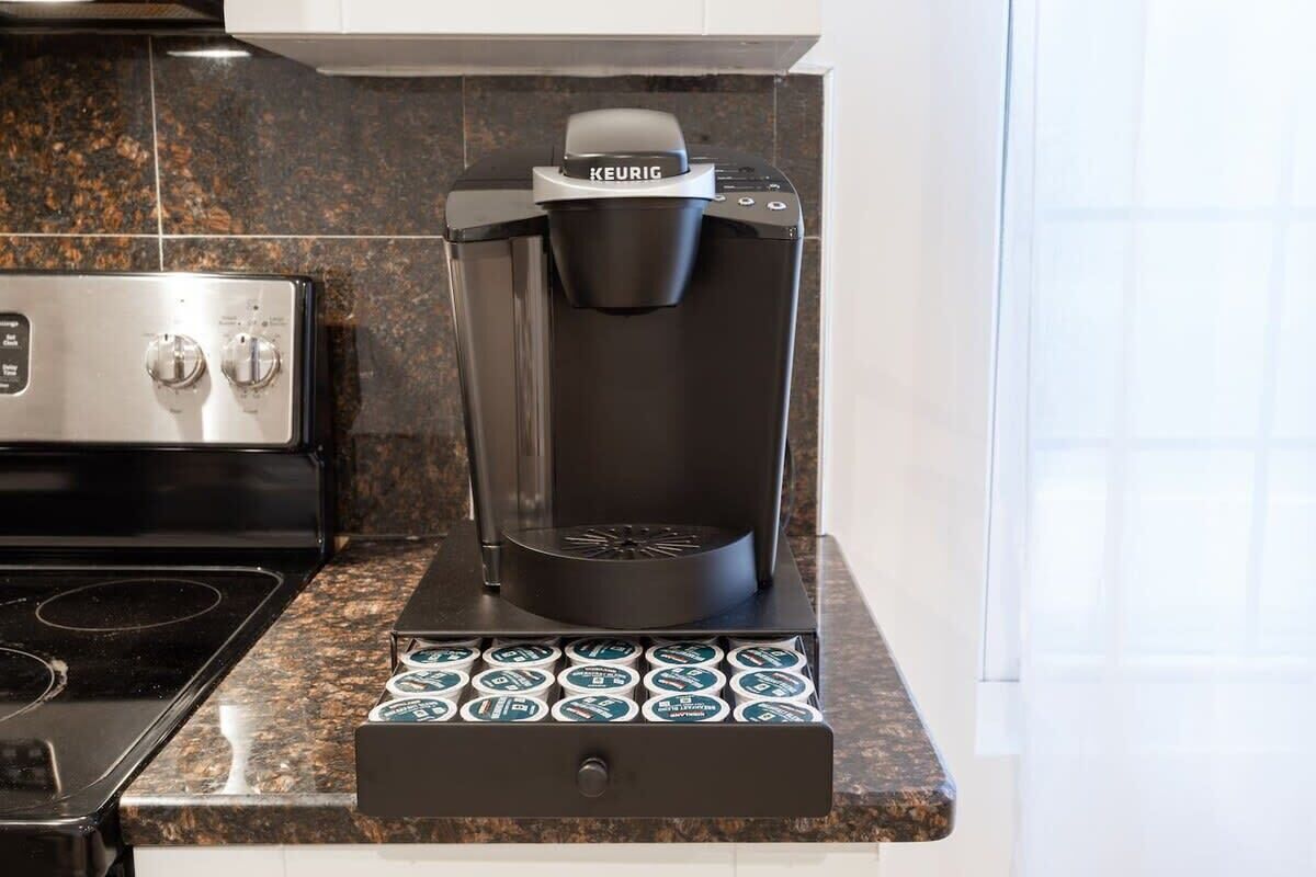 A Keurig coffee maker on a granite countertop with a coffee pod drawer below.