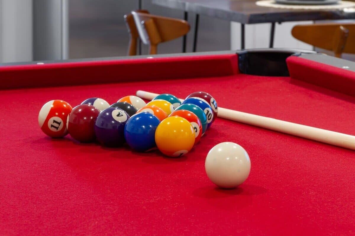 Une table de billard recouverte d’un drap de feutre rouge, avec une bille blanche.