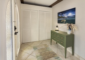 A room with a closed white closet, a green dresser with drawers, a small table with a candle, and a painting on the wall. - Beachfront!  Incredible Location, Amenities, and Views! (St. Thomas)