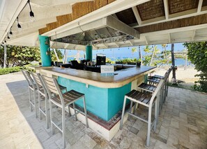 An outdoor bar area with a counter, stools, and a view of the beach. - Beachfront!  Incredible Location, Amenities, and Views! (St. Thomas)