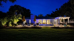 A house with a covered patio, outdoor seating, and a pool. - Modern Coastal Pool Retreat • Private Heated Pool • Minutes to Siesta Key Beach (Sarasota)
