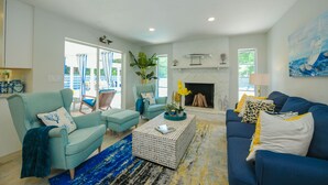 A living room with a fireplace, two armchairs, a sofa, and a coffee table. - Modern Coastal Pool Retreat • Private Heated Pool • Minutes to Siesta Key Beach (Sarasota)