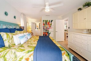 Ein Schlafzimmer mit einem Bett, einem Deckenventilator, einem Nachttisch und einer Kommode.