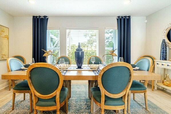 Une salle à manger avec une table en bois, quatre chaises et un vase.