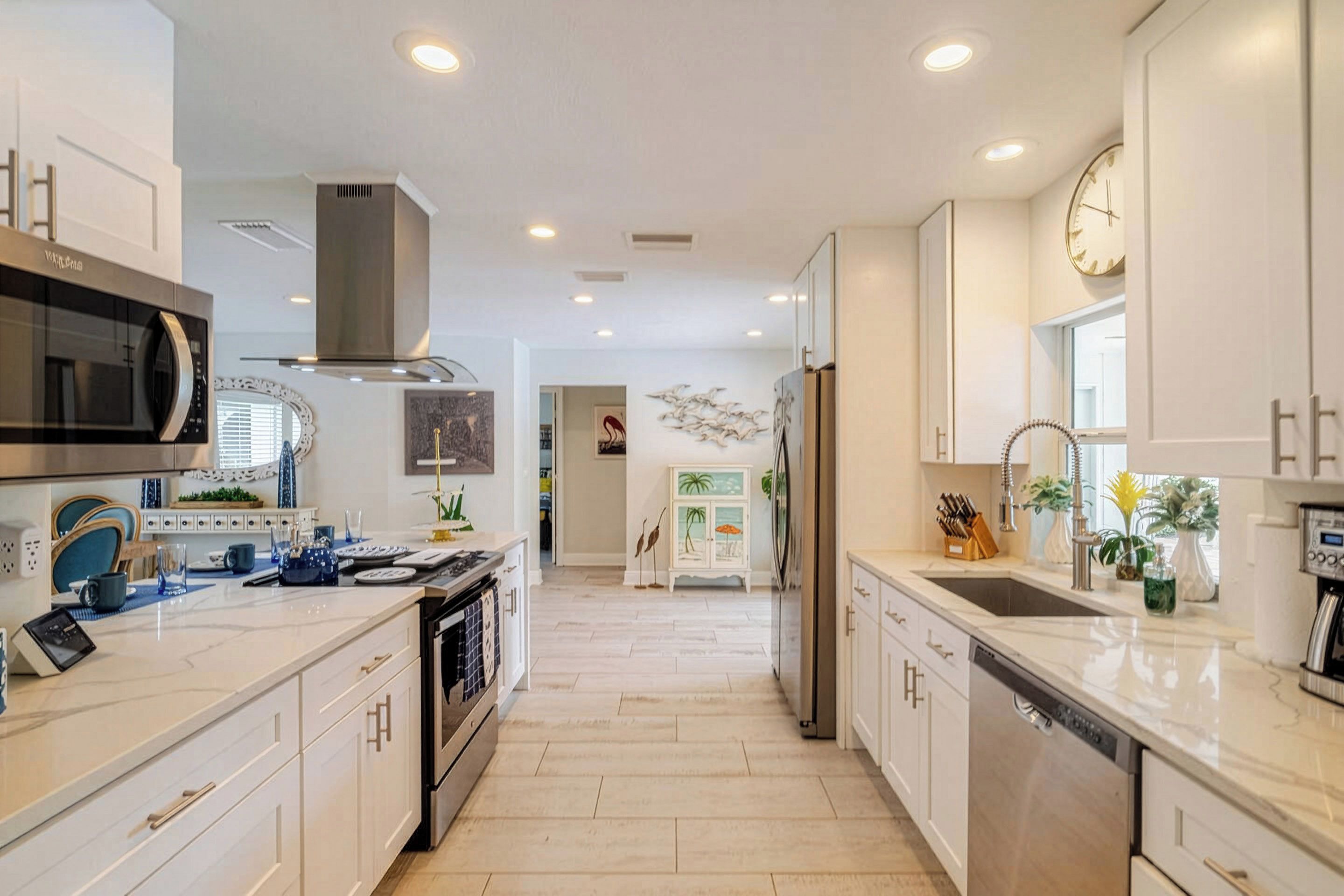 A modern kitchen with white cabinetry, stainless steel appliances, and a central island.