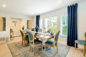 A dining room with a wooden table set for four, surrounded by chairs with cushioned seats.