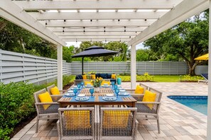 An outdoor patio with a covered dining area, wicker furniture, and a pool. - Modern Coastal Pool Retreat • Private Heated Pool • Minutes to Siesta Key Beach (Sarasota)
